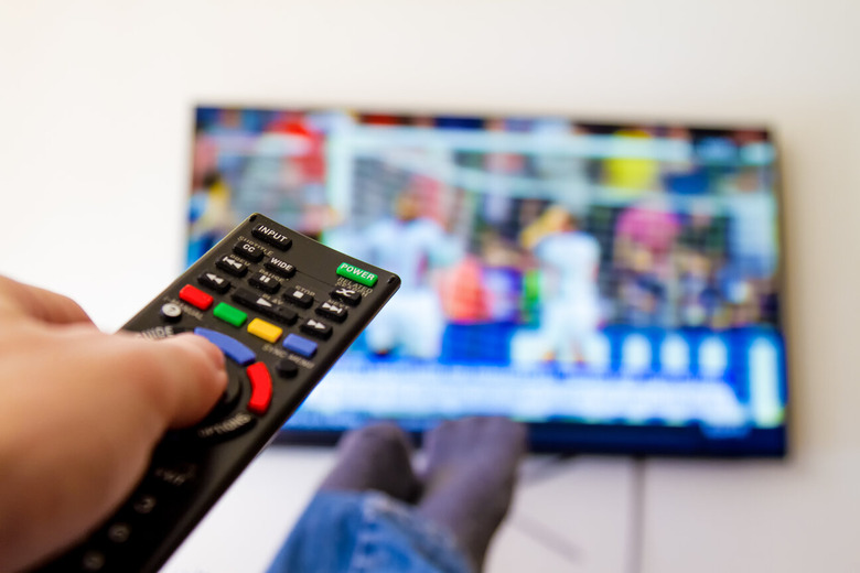 close-up of hand watching tv with remote