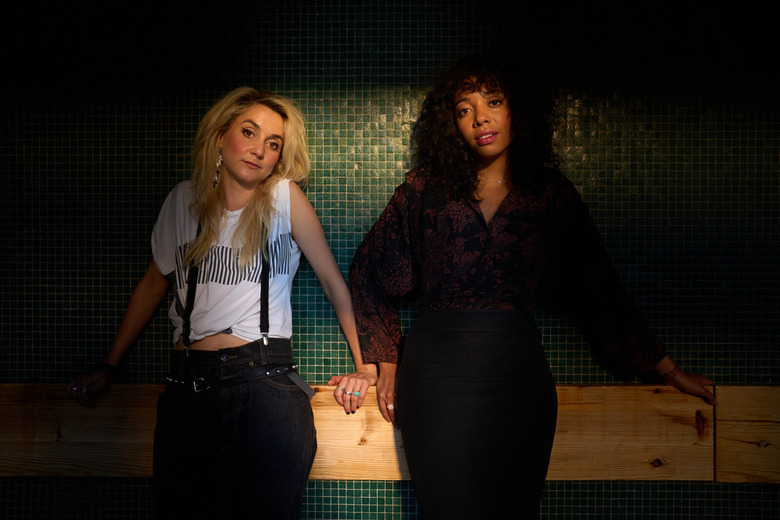two women stand in a dark room