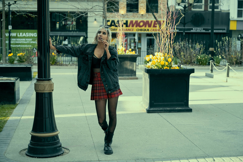 blonde woman leaning on a streetlamp