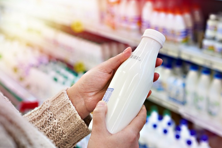 A person looking at a bottled milk drink at the grocery store.