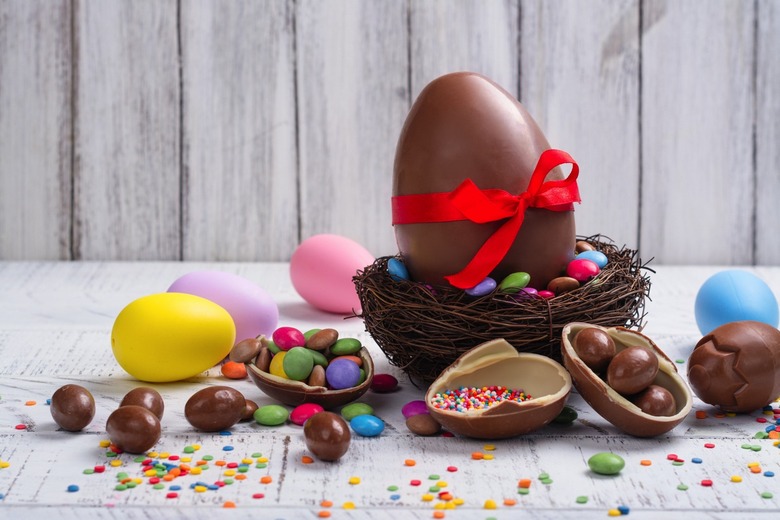 Easter chocolate egg and colorful candy sprinkles on white background