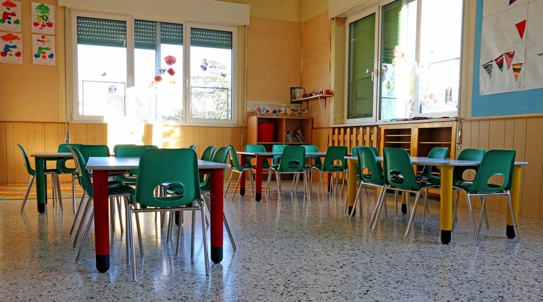 Interior of a kindergarten class with green chairs and children's decorations.