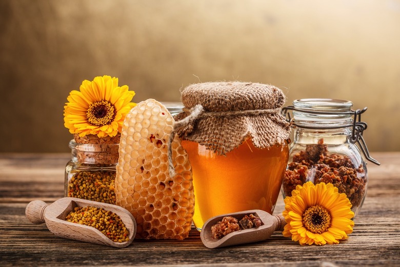 Honey, honeycomb, pollen, and propolis products on a table