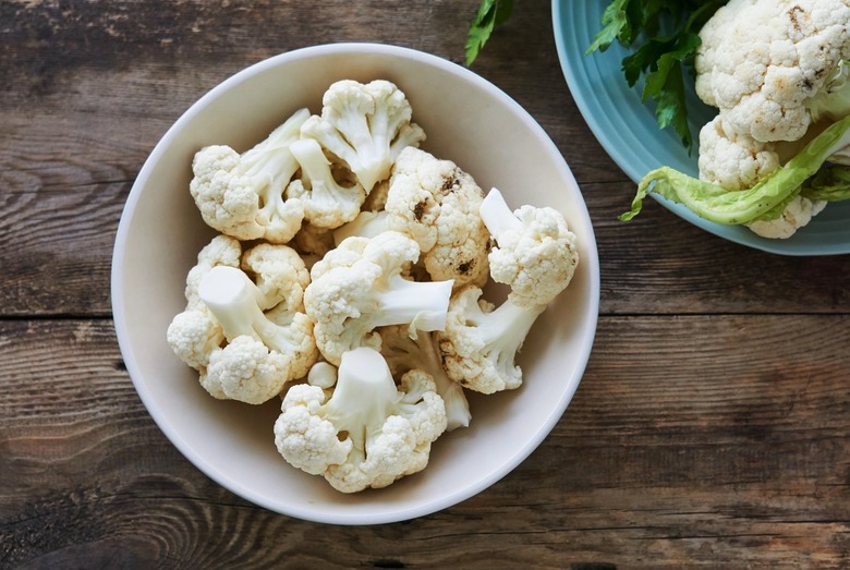 Pieces of raw cauliflower in a bowl on a wooden table