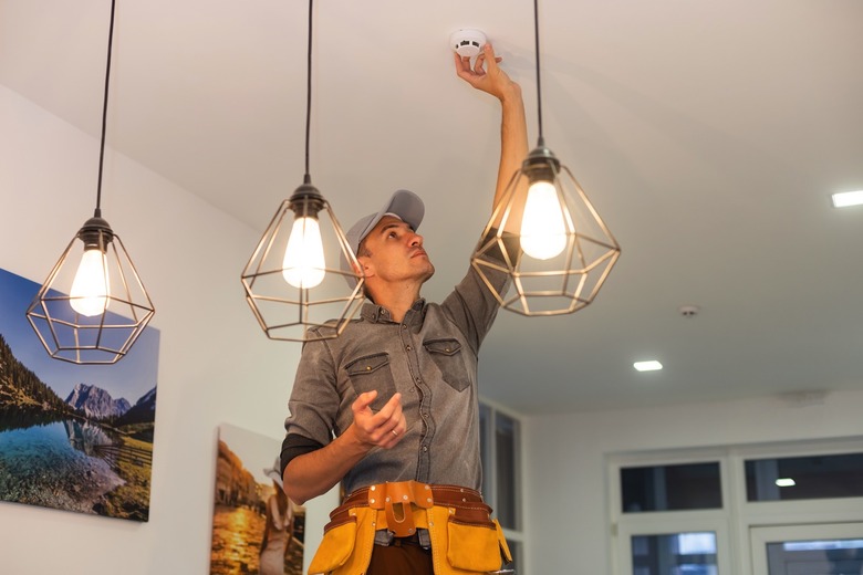 Handyman installing a smoke detector on the ceiling.