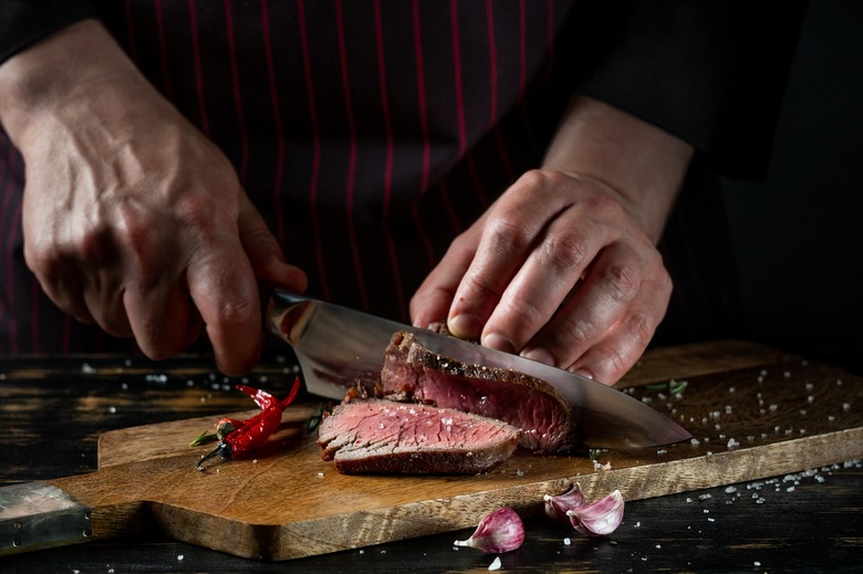 Slicing juicy beef steak by knife.