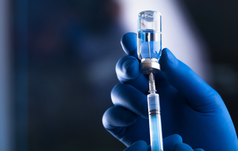 A doctor is shown holding a syringe and a drug vial.