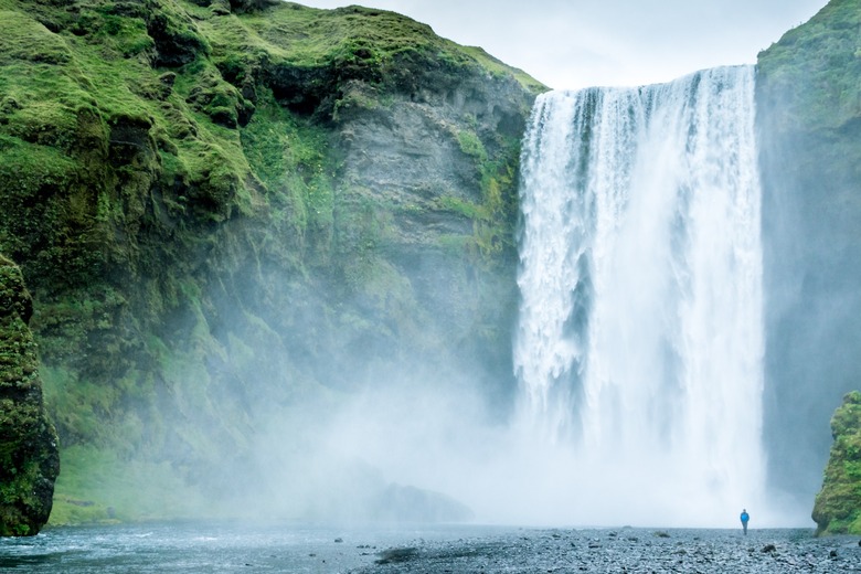 large waterfall with person standing in front of it