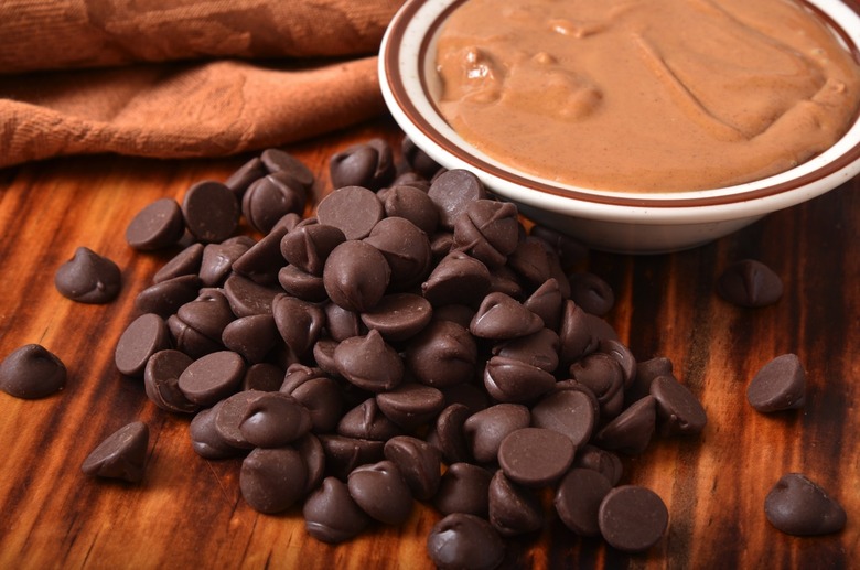 Closeup of dark chocolate chips with a bowl of peanut butter