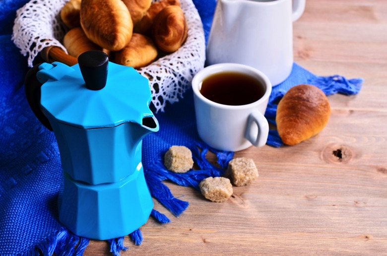 Coffee maker blue color on the background of croissants and utensils for coffee.