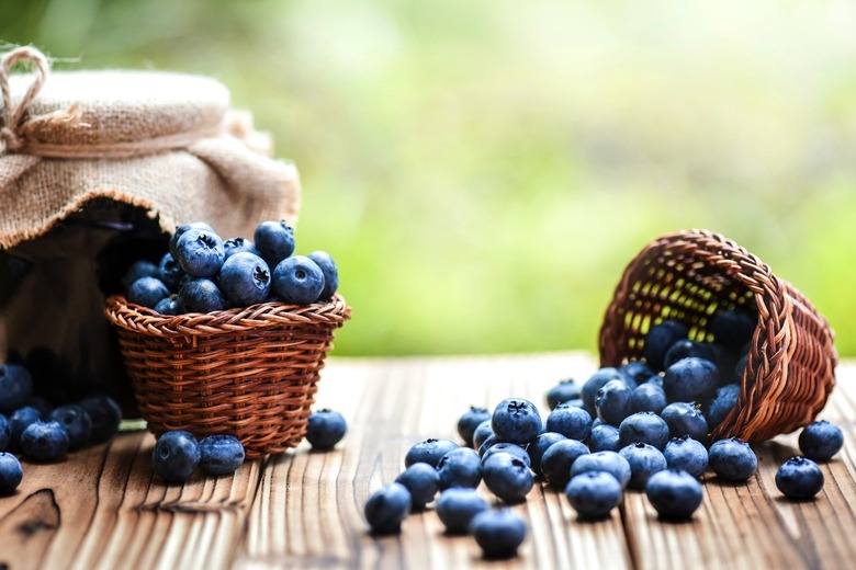 Blueberries in wicker basket on old table with back light.