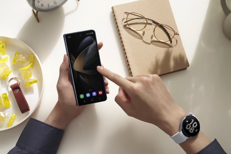 A person using the Galaxy Fold 4's cover screen and wearing a Galaxy Watch 5 device.