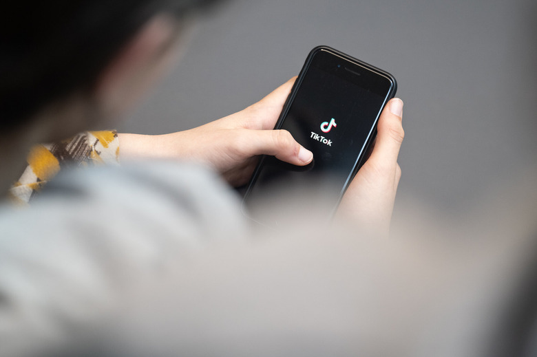 Young person holds a smartphone with TikTok logo