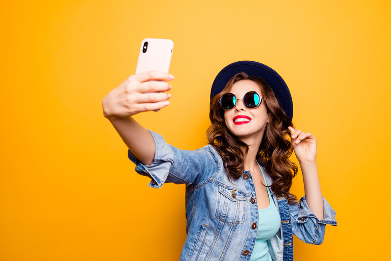 A girl is shown taking a selfie with a smartphone