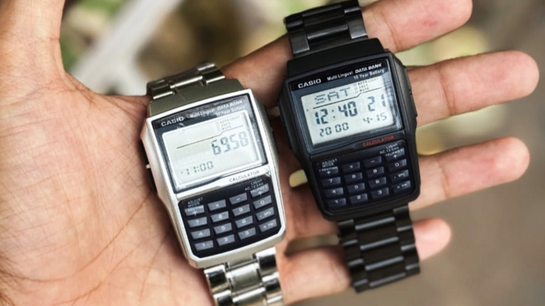 two Casio calculator watches held in the palm