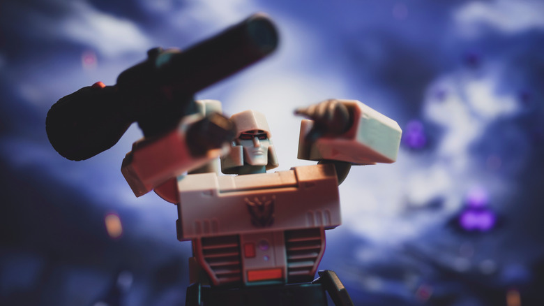 Megatron Transformers figure posed with an arm-mounted cannon in a cinematic close-up with blurred purple and blue background lighting.