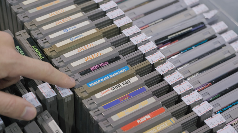 A hand sorts through NES game cartridges.