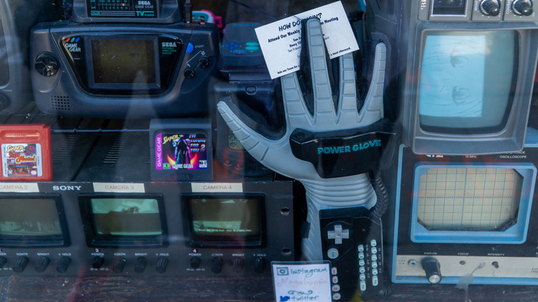 Display case filled with retro gaming and electronics hardware, including a Nintendo Power Glove.