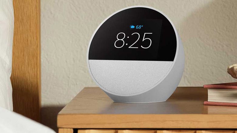 An Amazon smart speaker on a nightstand in a bedroom.