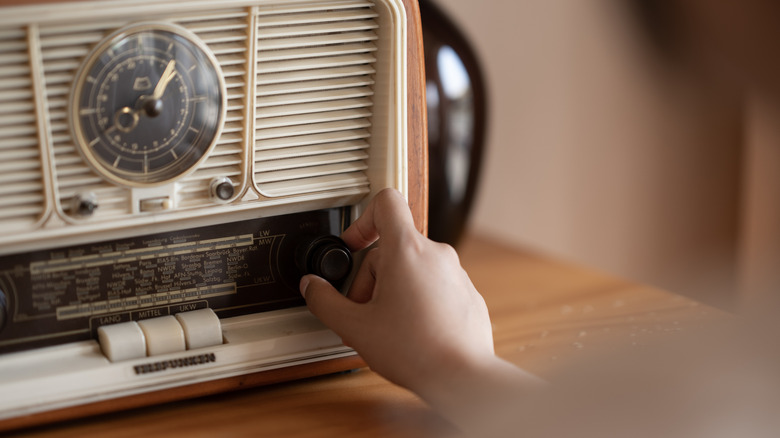A hand tuning a vintage radio.
