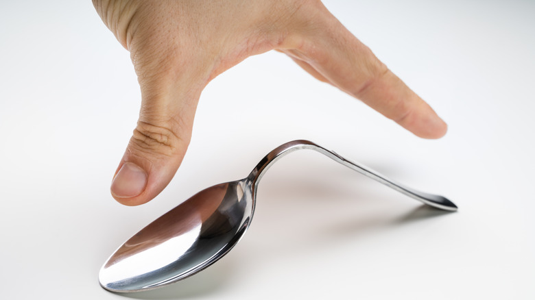 A hand bending a spoon without touching it.
