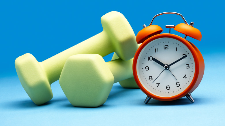 Alarm clock next to plastic dumb bells