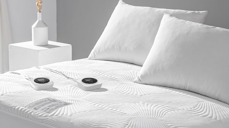 Reaks heating pad with two controllers with two pillows on the bed