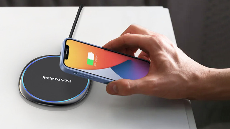 A hand placing a phone on the Nanami U6 wireless charging pad.