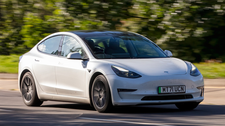 Tesla Model 3 driving on road in the countryside