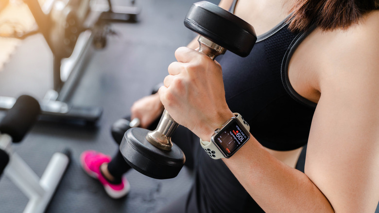 A person working out, wearing an Apple Watch showing their heart rate.