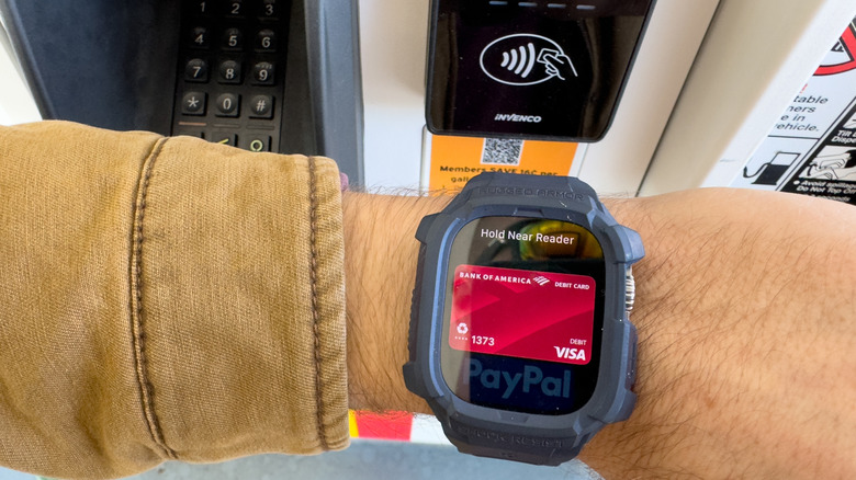 A person using Apple Pay on an Apple Watch at a gasoline station.