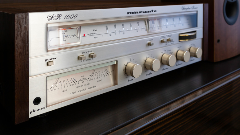 A vintage Marantz SR 1000 stereo receiver with analog radio tuner, illuminated power meters, and brushed aluminum controls housed in a woodgrain cabinet.