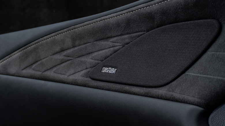 Close-up of a Mark Levinson-branded speaker integrated into a premium car door panel, showcasing the luxury audio system and suede-trimmed interior.