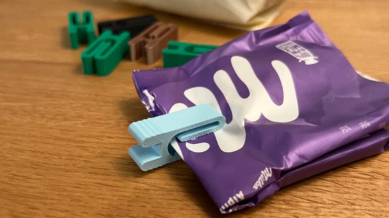 Mini bag clip wrapped around a candy wrapper on a wooden desk