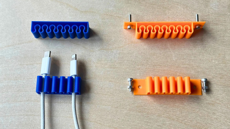 Several cable organizers with screws on the sides, sitting on a wooden table