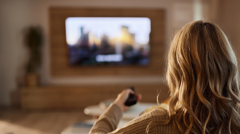 A person pointing a remote at the TV in the living room