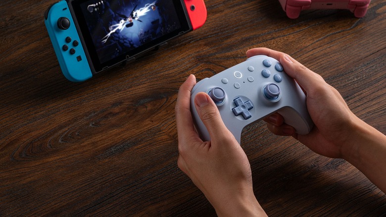Person playing Nintendo Switch with blue 8BitDo 2C controller