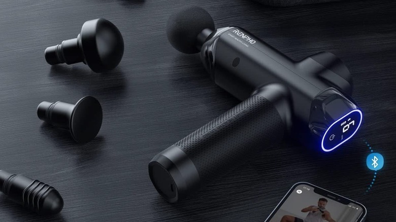Renpho Power Massage Gun with head attachments and phone on table