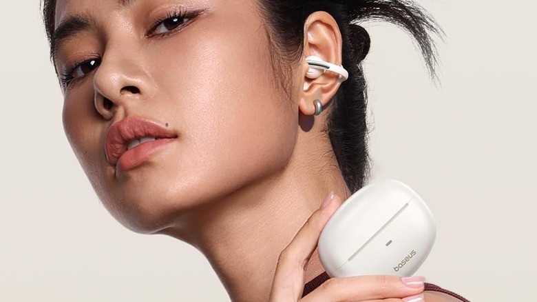 A woman wearing the Baseus Bowie MC1 clip-on earbuds while holding their charging case.