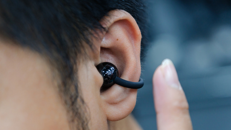 A person wearing a clip-on earbud in their ear.