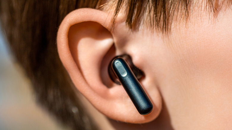 A person wearing a wireless earbud in their ear.