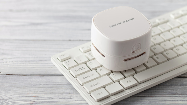 A desktop vacuum cleaner placed on a white keyboard