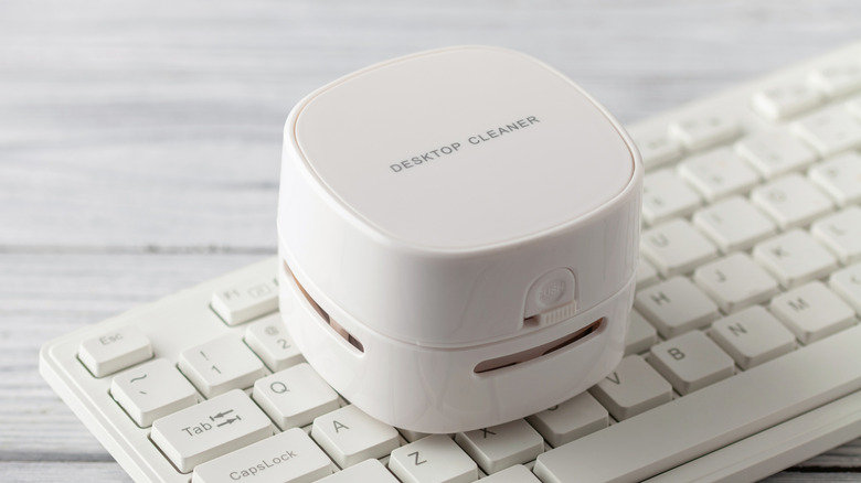 A desktop vacuum cleaner placed on a white keyboard