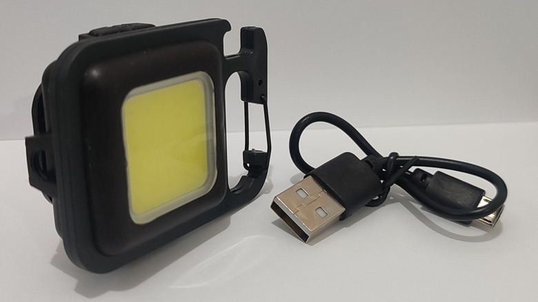 A close-up shot of a rechargeable keychain light with a USB cable