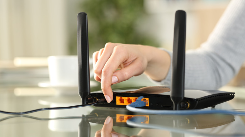 A man handling a high-speed internet router with an ethernet cable plugged in
