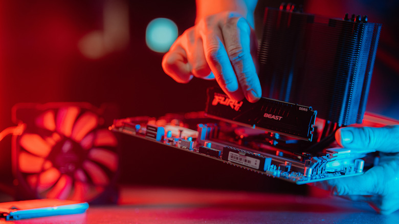 Man inserting a RAM stick into a motherboard