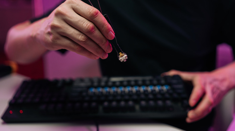 A man pulling out a switch from a mechanical keyboard