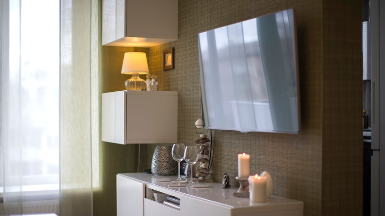 A wall-mounted TV with excessive glare from a nearby window.