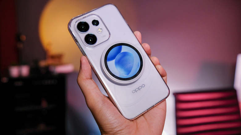 A person holding a Oppo Reno 16 phone with the Bubble screen accessory attached