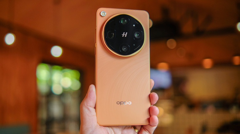A person holding the Oppo Find X9 Ultra in the Orange Color